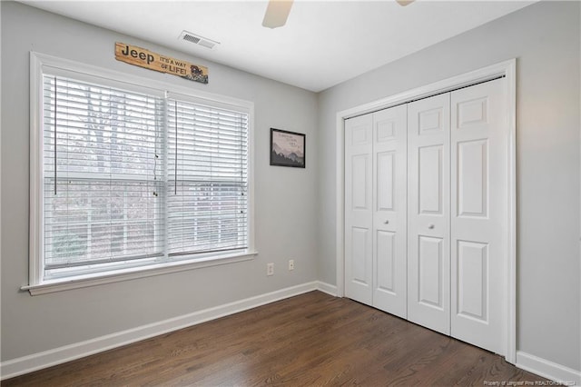 unfurnished bedroom with a closet, dark wood-type flooring, and ceiling fan