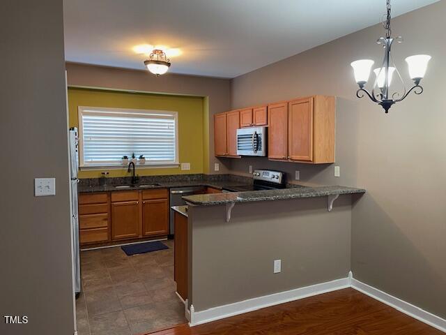 kitchen with sink, hanging light fixtures, stainless steel appliances, a kitchen bar, and kitchen peninsula