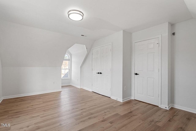 additional living space with light hardwood / wood-style flooring and vaulted ceiling