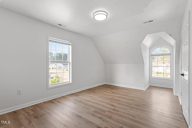 bonus room with light wood-type flooring and vaulted ceiling