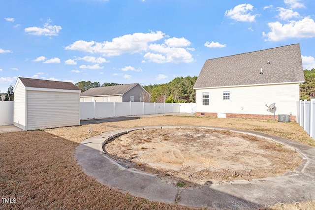 view of yard featuring central AC unit and a storage shed