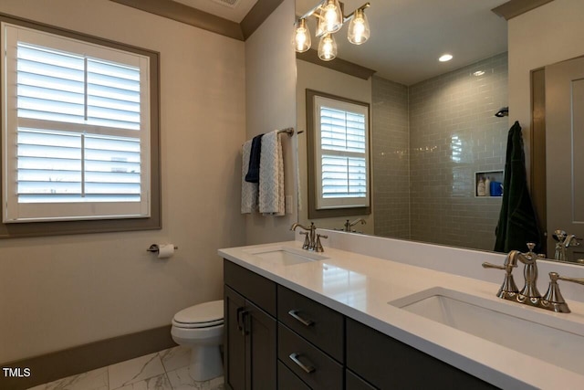 bathroom with toilet, a tile shower, and vanity