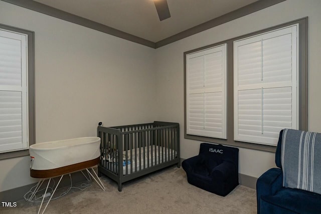 carpeted bedroom with ceiling fan and a nursery area