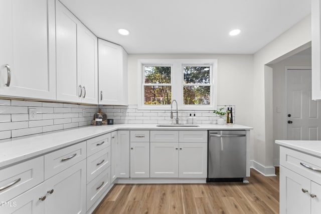 kitchen with dishwasher, sink, light hardwood / wood-style flooring, decorative backsplash, and white cabinetry