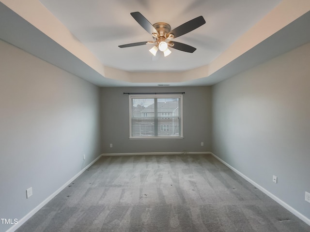 carpeted empty room featuring a tray ceiling and ceiling fan