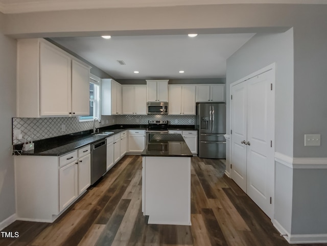 kitchen with dark hardwood / wood-style floors, a kitchen island, white cabinetry, and appliances with stainless steel finishes