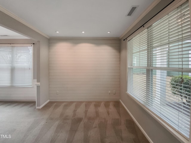 unfurnished room featuring a wealth of natural light, light colored carpet, and ornamental molding