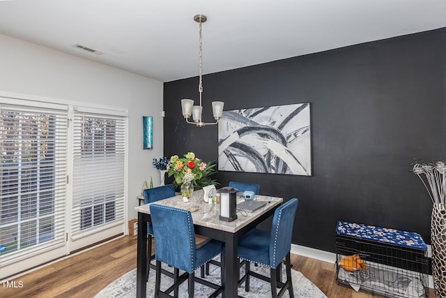 dining space with dark hardwood / wood-style floors and a notable chandelier