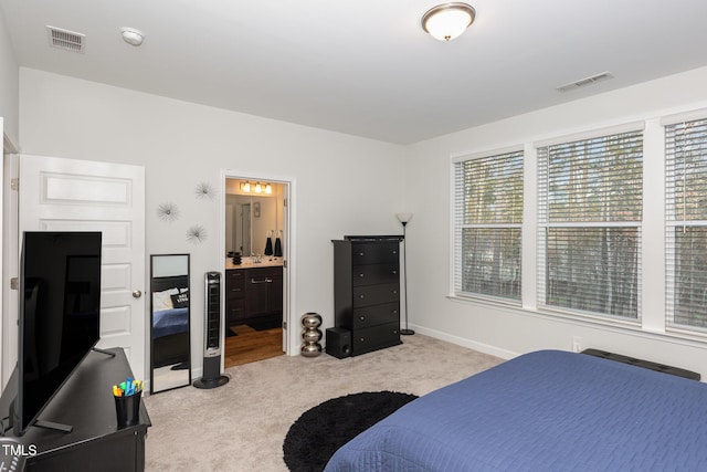 bedroom featuring ensuite bathroom and light carpet