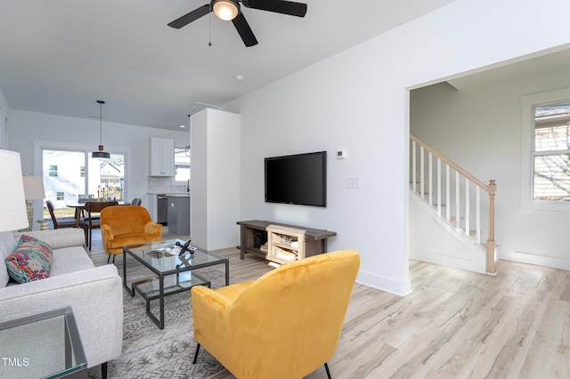 living room with ceiling fan, plenty of natural light, and light hardwood / wood-style flooring