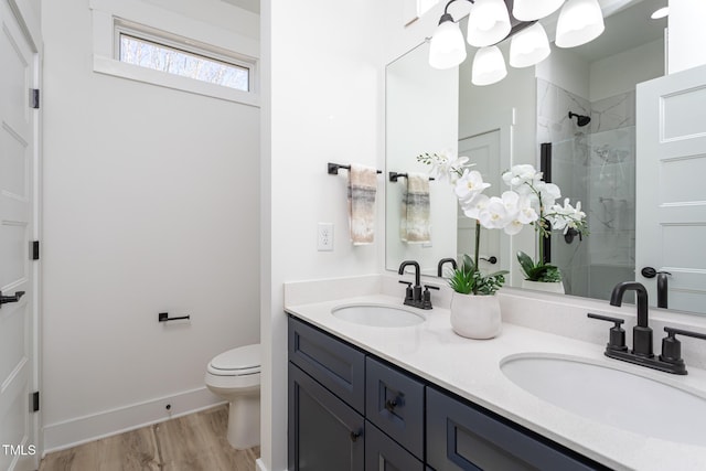 bathroom featuring toilet, vanity, a tile shower, and hardwood / wood-style flooring