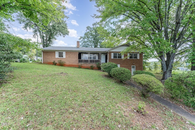 ranch-style home featuring brick siding, a chimney, and a front yard