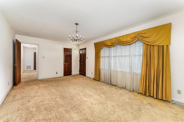 unfurnished room featuring baseboards, visible vents, carpet, a textured ceiling, and a notable chandelier