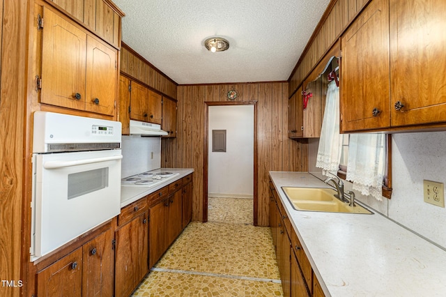 kitchen with light countertops, white appliances, a sink, and under cabinet range hood