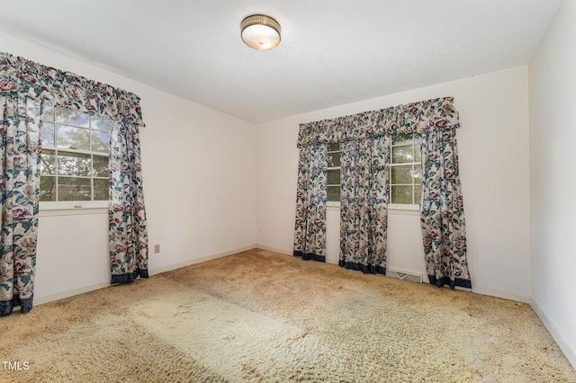 empty room with carpet, visible vents, baseboards, and a textured ceiling