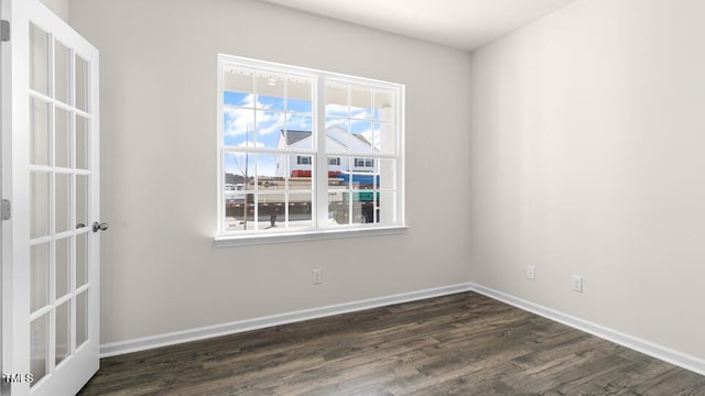 spare room featuring dark wood-style floors and baseboards