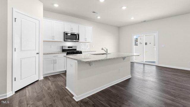 kitchen with a sink, white cabinets, dark wood-style floors, and stainless steel appliances