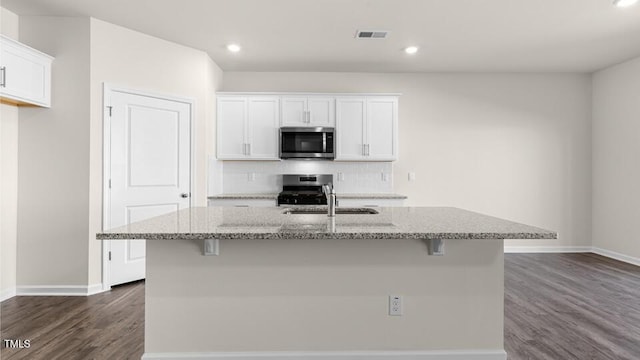 kitchen with light stone countertops, visible vents, a sink, appliances with stainless steel finishes, and tasteful backsplash