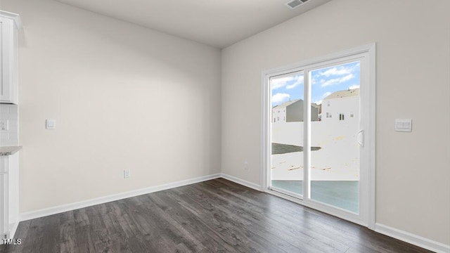 unfurnished room featuring visible vents, baseboards, and dark wood finished floors