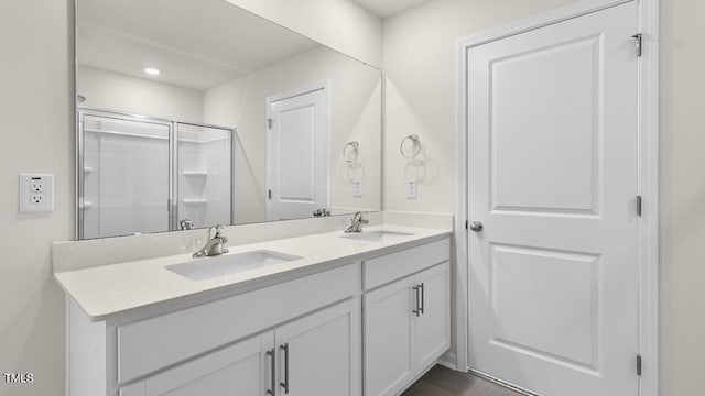 bathroom with a sink, a shower stall, recessed lighting, and double vanity