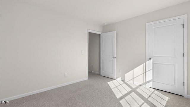 spare room with light colored carpet and baseboards