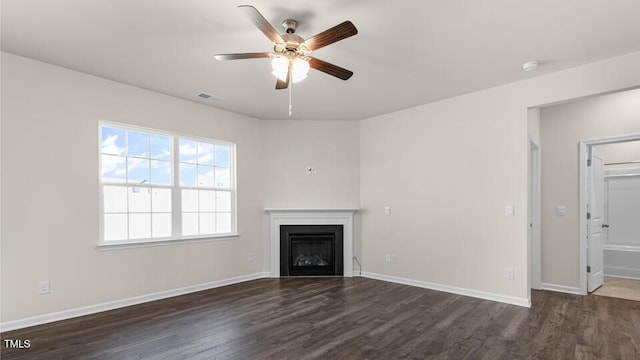 unfurnished living room with a glass covered fireplace, visible vents, baseboards, and wood finished floors