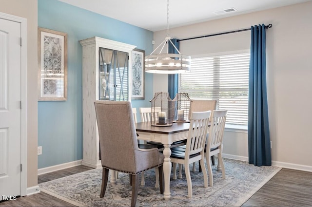 dining room with dark wood-type flooring and a chandelier