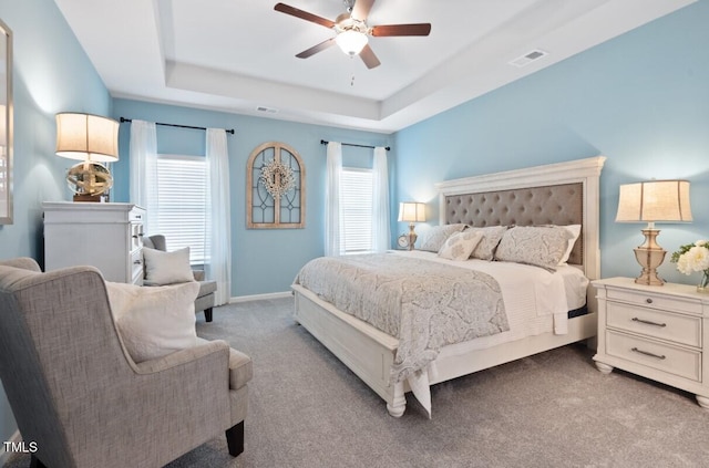 carpeted bedroom with a tray ceiling and ceiling fan