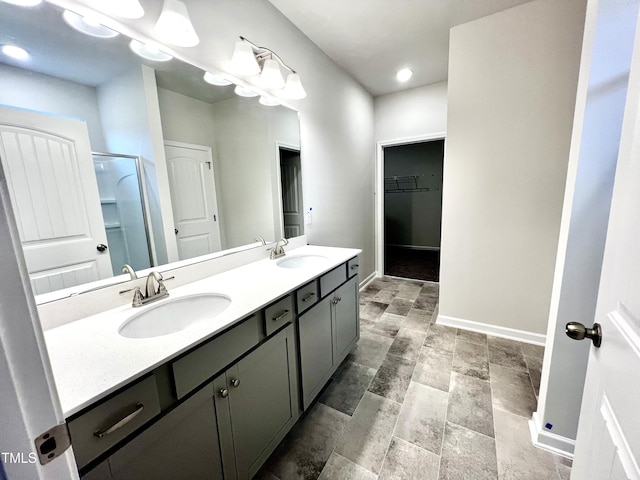full bathroom featuring double vanity, baseboards, and a sink