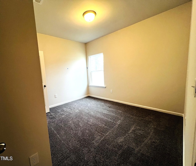 spare room featuring visible vents, baseboards, and dark colored carpet