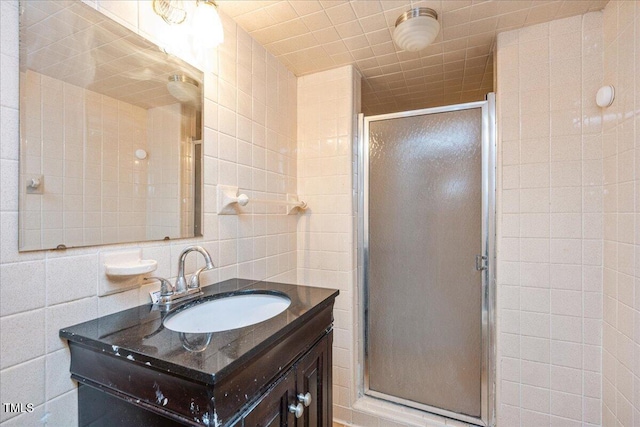 bathroom with walk in shower, decorative backsplash, vanity, and tile walls