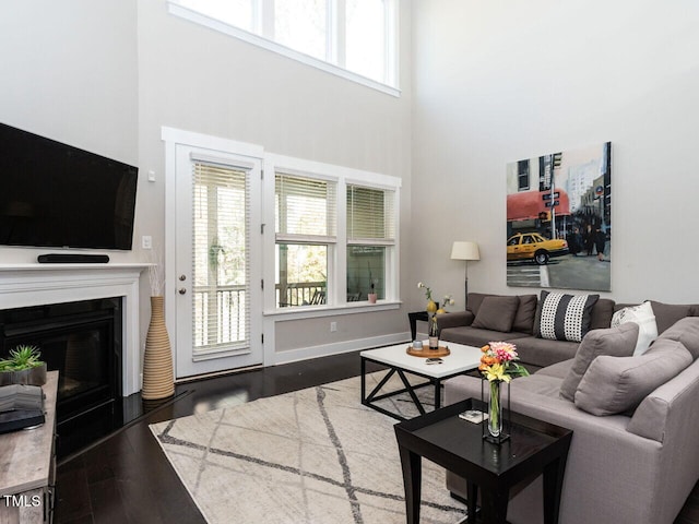 living room featuring a wealth of natural light, dark hardwood / wood-style flooring, and a high ceiling