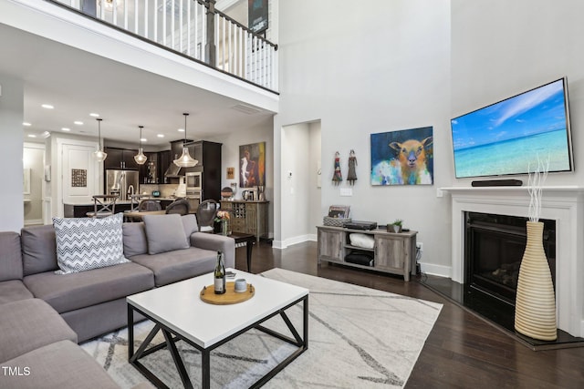 living room featuring dark hardwood / wood-style flooring and a towering ceiling