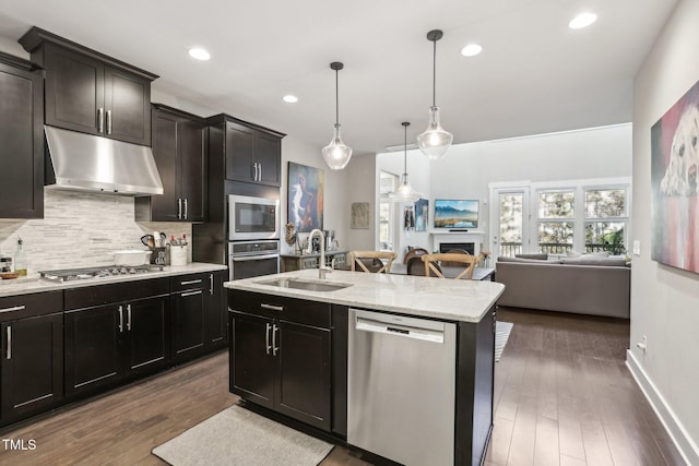 kitchen featuring appliances with stainless steel finishes, dark hardwood / wood-style flooring, sink, decorative light fixtures, and an island with sink