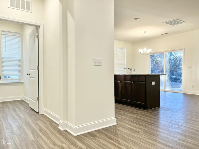 corridor featuring an inviting chandelier, light hardwood / wood-style flooring, and sink