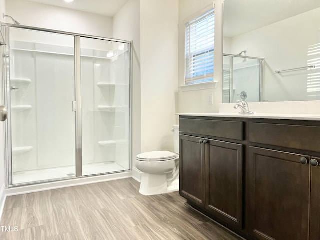 bathroom featuring a shower with door, vanity, hardwood / wood-style floors, and toilet