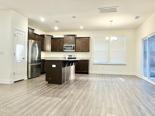 kitchen with a center island, light hardwood / wood-style floors, appliances with stainless steel finishes, and an inviting chandelier