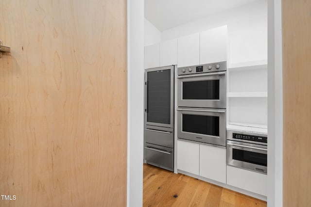 kitchen featuring white cabinets, light hardwood / wood-style floors, and double oven