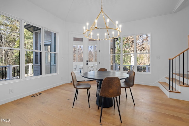 dining area featuring a chandelier, light wood-type flooring, and vaulted ceiling