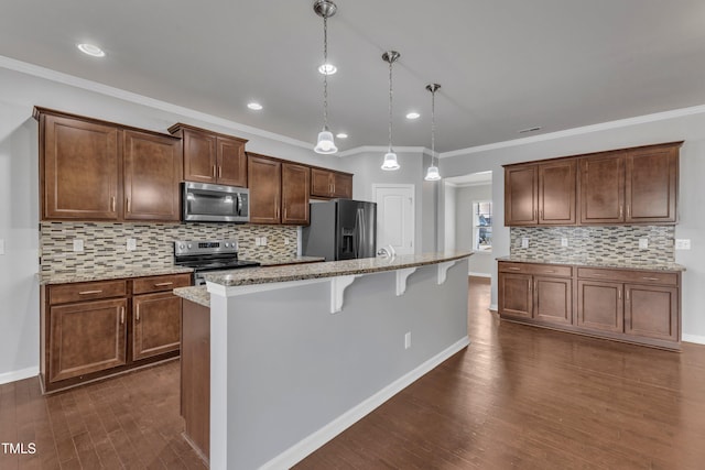 kitchen with a kitchen island, hanging light fixtures, appliances with stainless steel finishes, and a breakfast bar area