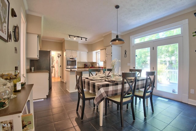 dining room featuring rail lighting, a textured ceiling, crown molding, and dark tile patterned flooring