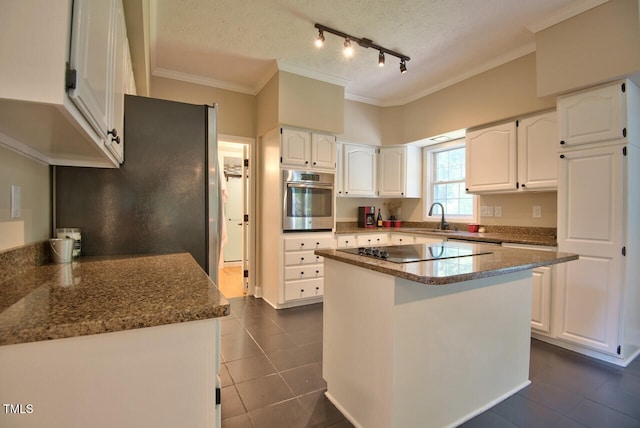 kitchen with dark stone counters, white cabinets, appliances with stainless steel finishes, ornamental molding, and a sink