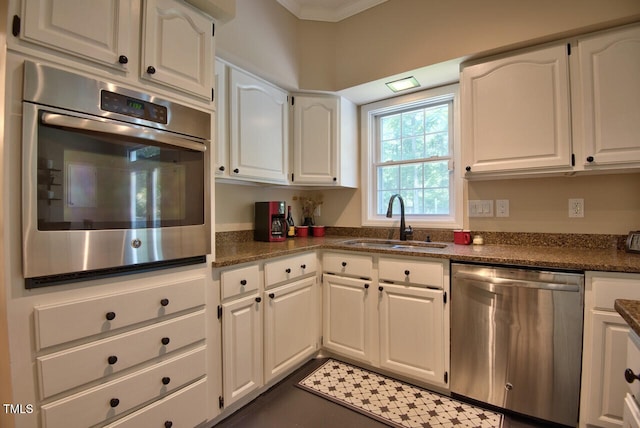 kitchen with dark stone counters, appliances with stainless steel finishes, a sink, and white cabinetry