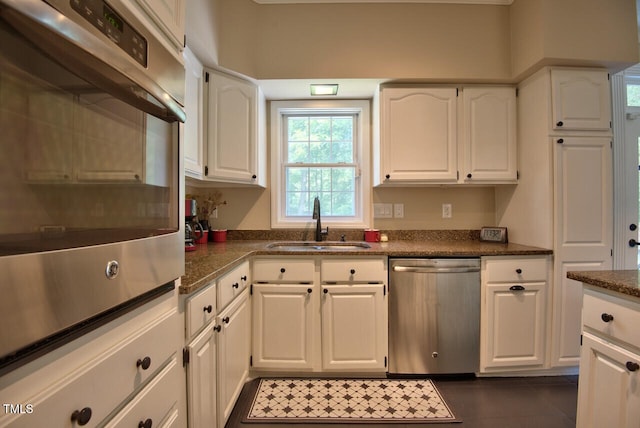 kitchen featuring white cabinets, dark tile patterned floors, stainless steel appliances, and a sink