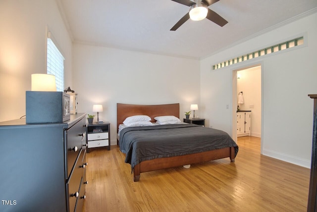 bedroom featuring ceiling fan, ensuite bathroom, baseboards, light wood-style floors, and crown molding