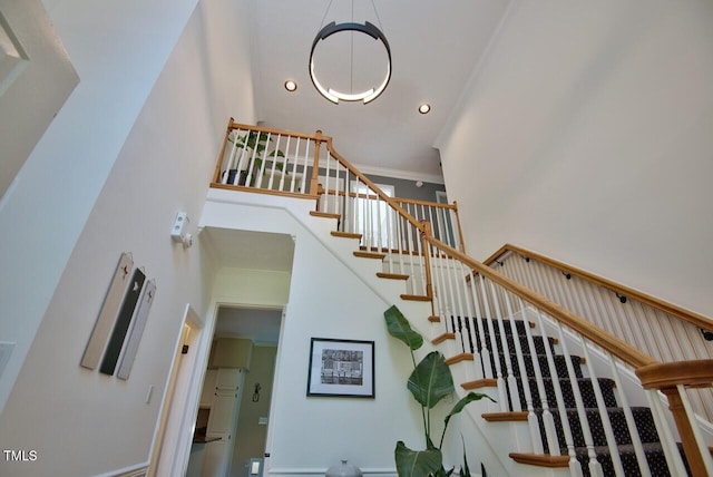 staircase featuring a towering ceiling, crown molding, and recessed lighting