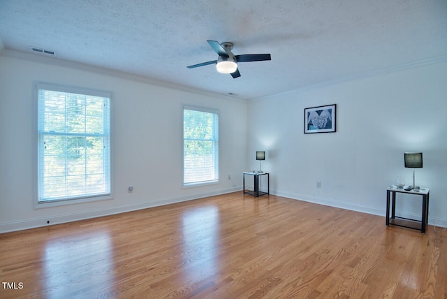 spare room with visible vents, crown molding, light wood-style flooring, and a textured ceiling