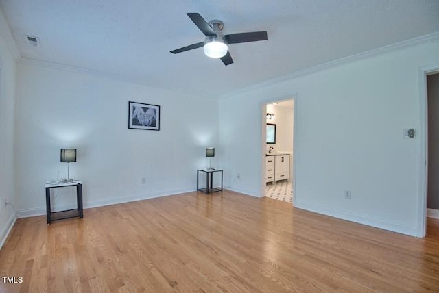 empty room featuring baseboards, light wood-type flooring, visible vents, and crown molding