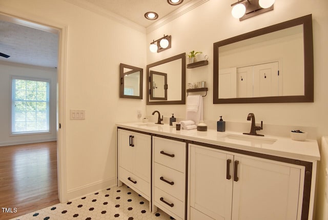 bathroom with ornamental molding, a sink, baseboards, and double vanity