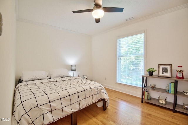 bedroom with wood finished floors, a ceiling fan, visible vents, baseboards, and ornamental molding